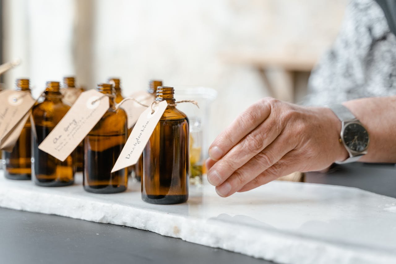 Close-up of essential oil bottles with handwritten labels and a hand reaching for one.